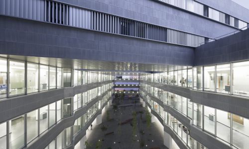 Facultad de Ciencias de la Educación en Sevilla Diseño exterior nocturno de fachada interior de patio acristalada cubierta por pasarela de Cruz y Ortiz Arquitectos