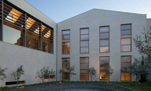 Lofts en Fabrica de Sabadell en Barcelona Diseño exterior de fachada interior de patio a jardin de patio elíptico con mobiliario exterior de banco de piedra de Cruz y Ortiz Arquitectos