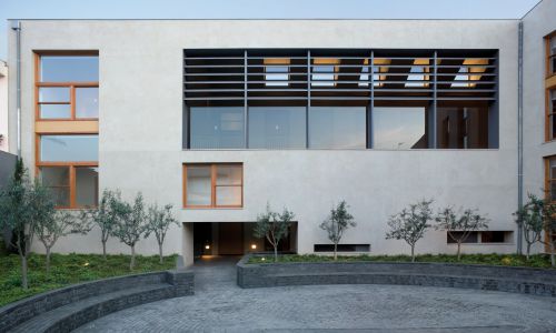 Lofts en Fabrica de Sabadell en Barcelona Diseño exterior de fachada interior de patio a jardin en patio con mobiliario de banco en forma de elipse de Cruz y Ortiz Arquitectos