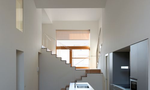 Lofts en Fabrica de Sabadell en Barcelona Diseño interior de cocina escalera de madera con pasamanos metálico en espacio a doble altura de Cruz y Ortiz Arquitectos