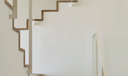 Lofts en Fabrica de Sabadell en Barcelona Diseño interior de escalera de madera con pasamanos de acero blanco de Cruz y Ortiz Arquitectos